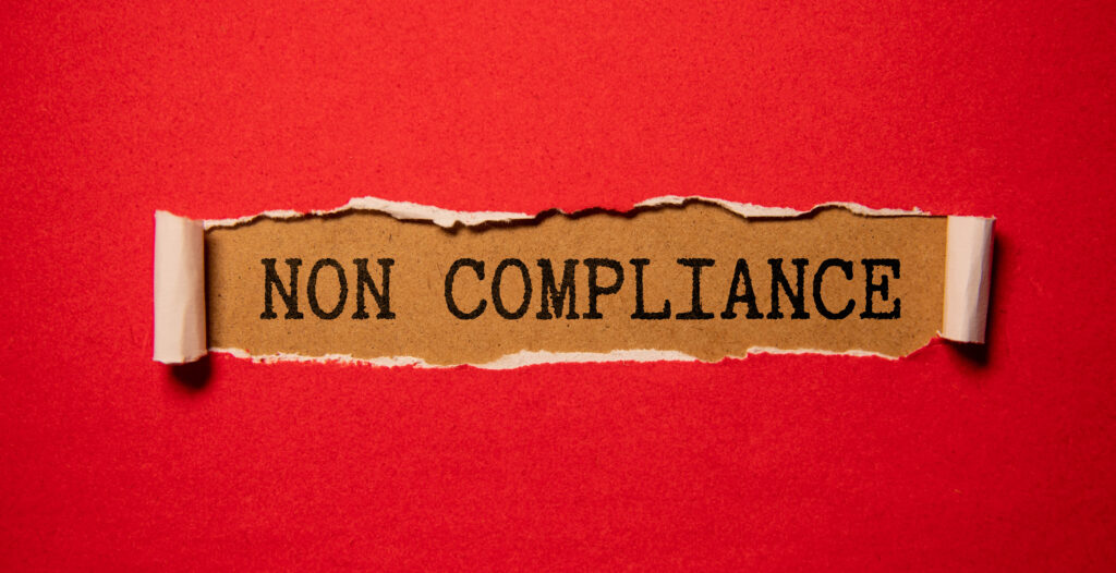 Non-complicance written underneath a tear in a red paper.